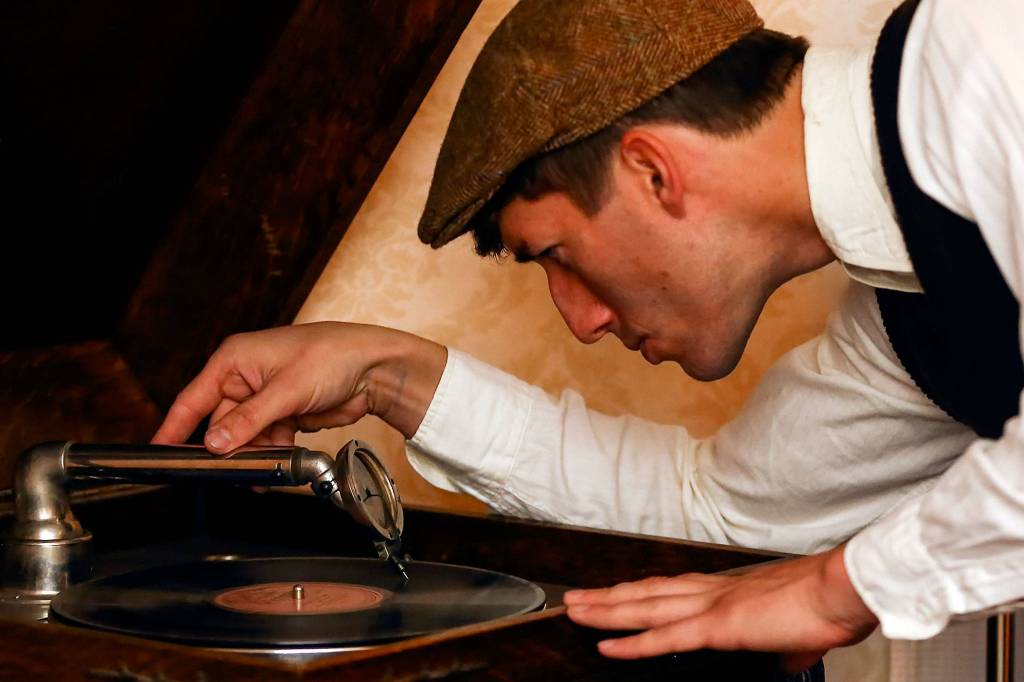 Edmundo Olanu drops the tone arm on a vintage phonograph. (Kevin Clark / The Herald)