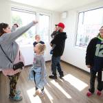 Lisa Collier (left) cheers for her cousin Andrew Pliss (in red hat) as they tour a two-bedroom apartment, where Andrew will soon live with this kids Riley and Chelsea, at HopeWorks Station on Friday. (Andy Bronson / The Herald)