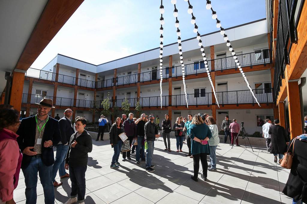 Hundreds of people wander around apartments and the courtyard at HopeWorks Station on Friday. (Andy Bronson / The Herald)
