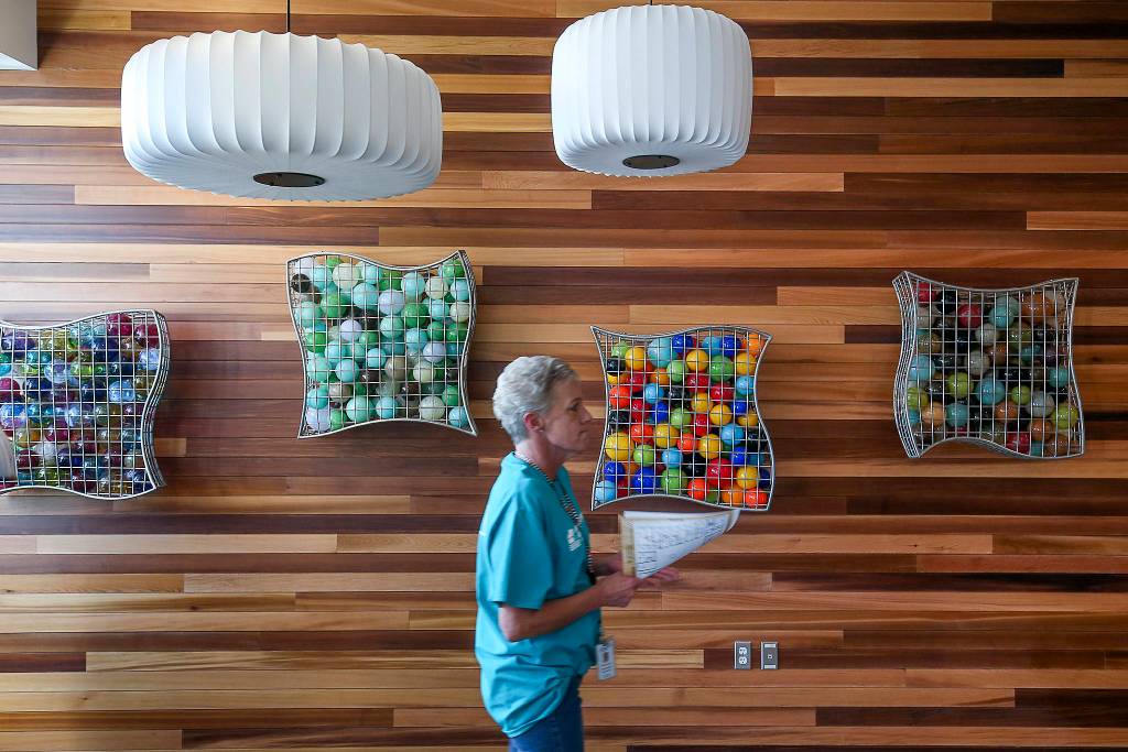 A woman wanders past artwork in the main hallway at HopeWorks Station after an opening ceremony Friday. (Andy Bronson / The Herald)