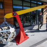 Gabriele Mezzato and Katie Austin, of Dykeman Architects, ring a bell after pulling down on an art piece entitled Leverage in front of HopeWorks Station on Friday. (Andy Bronson / The Herald)