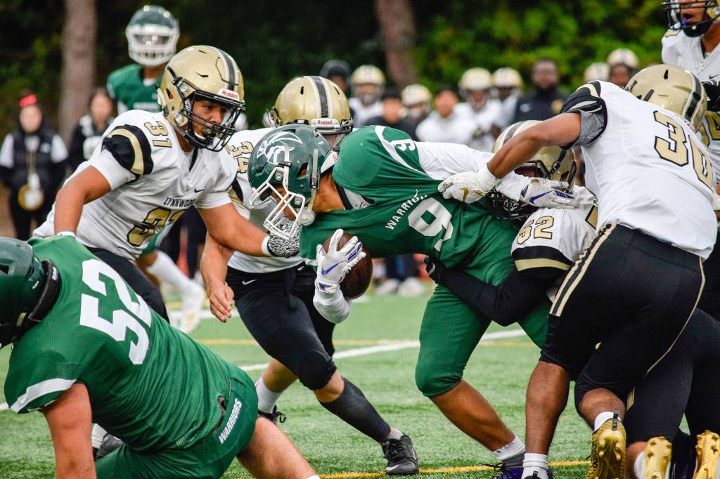 The Lynnwood defense swarms Edmonds-Woodway junior running back Steele Swinton on Friday at Edmonds Stadium. (Katie Webber / The Herald)