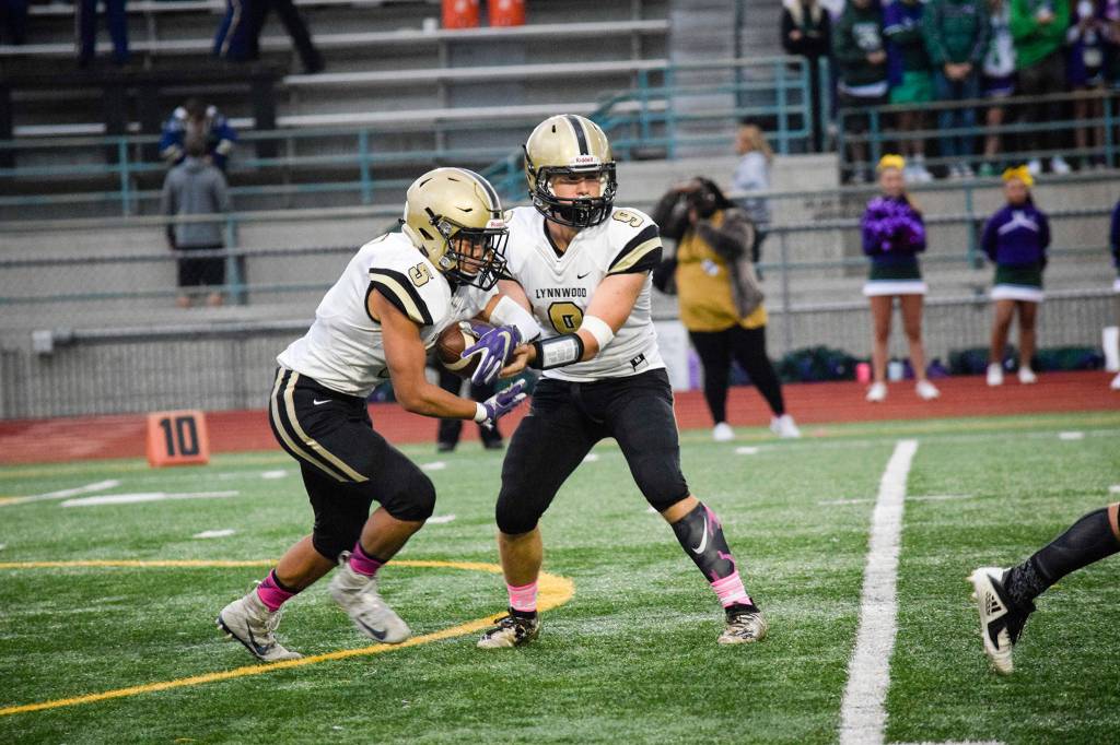 Senior quarterback Nate Killen hands off the ball to senior running back Daniel Tran against Edmonds-Woodway on Friday at Edmonds Stadium. (Katie Webber / The Herald)