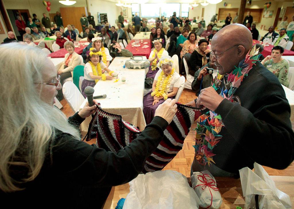 Debra Loughrey-Johnson helps Carl Gipson open a package of knitted gifts made by members of the Carl Gipson Senior Center during a party on Jan. 11, 2014, celebrating his 90th birthday. (Annie Mulligan / Herald file)