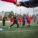 Everett Community Colleges Olivia Lee (left) and Elizabeth Erickson hold hands in the center of a circle during a passing drill during the Trojans team practice on Oct. 8 at Kasch Park in Everett. (Olivia Vanni / The Herald)