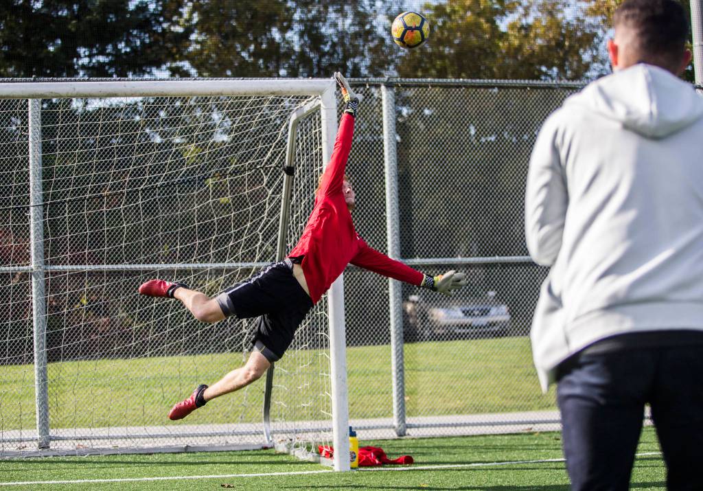 Everett Community College mens soccer goalkeeper Cameron Beardsley dives to make a save during the Trojans Oct. 8 practice at Kasch Park in Everett. (Olivia Vanni / The Herald)