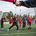 Olivia Lee, left, and Elizabeth Erickson hold hands in the center of the circle for a passing drill during practice on Tuesday, Oct. 8, 2019 in Everett, Wash. (Olivia Vanni / The Herald)