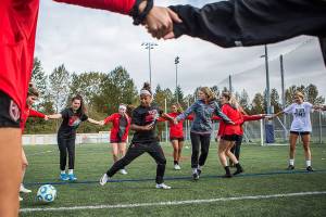 Olivia Lee, left, and Elizabeth Erickson hold hands in the center of the circle for a passing drill during practice on Tuesday, Oct. 8, 2019 in Everett, Wash. (Olivia Vanni / The Herald)