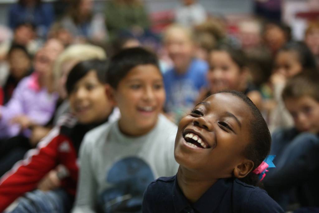 Florida Bernard, a third-grader, laughs at a joke made by Jake Shimabukuro, a renowned ukulele player, as he performs at Frank Wagner Elementary on Monday in Monroe. (Andy Bronson / The Herald)