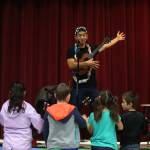Jake Shimabukuro shows students how to strum an open chord with one hand. (Andy Bronson / The Herald)