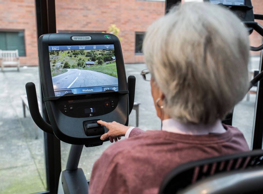 A screen screen shows a video of mountain road that moves at the same pace as your pedaling at the Carl Gipson Senior Centers new fitness room. (Olivia Vanni / The Herald)