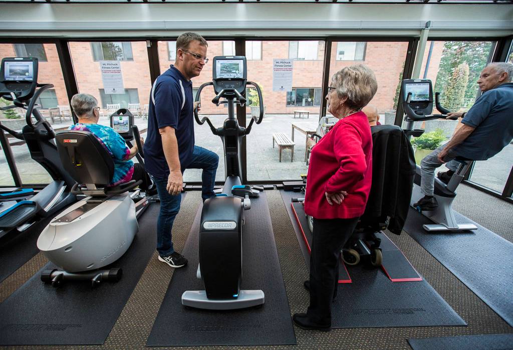 photos by Olivia Vanni / The Herald                                 Program coordinator Eric Wollan shows Doris Moran how to use the elliptical machine at the Carl Gipson Senior Centers new fitness room in Everett.