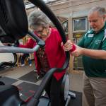 Bob Dvorak helps Moran onto the elliptical machine.