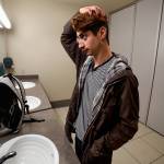 Humberto Villarruel, a 21-year-old Everett Community College student, uses the mirror in an all-gender restroom in the Parks Student Union on campus Tuesday. (Dan Bates / The Herald)