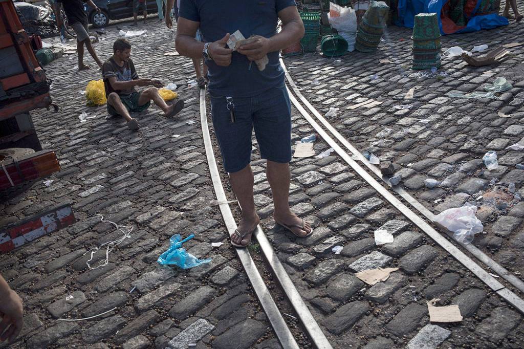 A vendor counts money as a man collects acai berries from the floor at the Ver-o-Peso riverside market. Global demand for the fruit expanded rapidly in the 21st century so the tree is cultivated primarily for that purpose. (AP Photo/Rodrigo Abd)