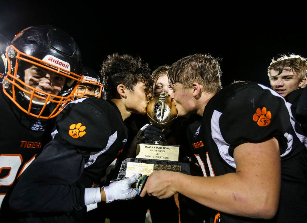 Granite Falls Mason McBride (left) and Blake Williams kiss the Black & Blue Bowl trophy after beating Sultan 45-0 on Friday in Granite Falls. (Olivia Vanni / The Herald)