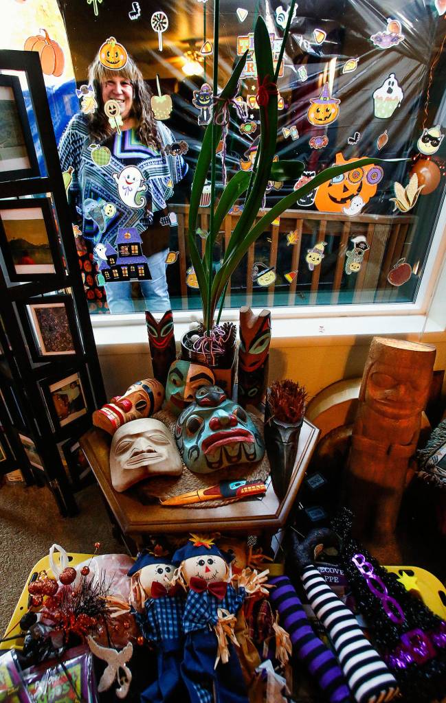 Ivy Fulmer, who lives on Everetts Chestnut Street, glances through a living room window she decorated for the delight of trick-or-treaters. Inside are other Halloween objects she has acquired as well as genuine carved Alaska Native masks (middle table) made by her husband, Fred Fulmer. (Dan Bates / The Herald)