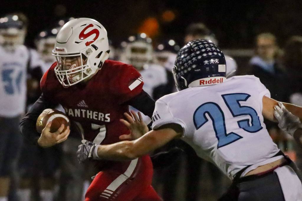 Snohomishs Silas Stehle (left) rushes with Meadowdales Jacob Wezenberg trailing Friday evening at Veterans Memorial Stadium in Snohomish on October 25, 2019. (Kevin Clark / The Herald)