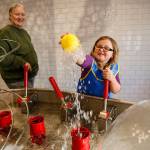 In this March 2018 photo, Madison Davis of Snohomish reaches into the air pocket of a water feature at the Imagine Childrens Museum in Everett, while her adopted grandmother Michele Tanis watches. (Dan Bates / Herald file)