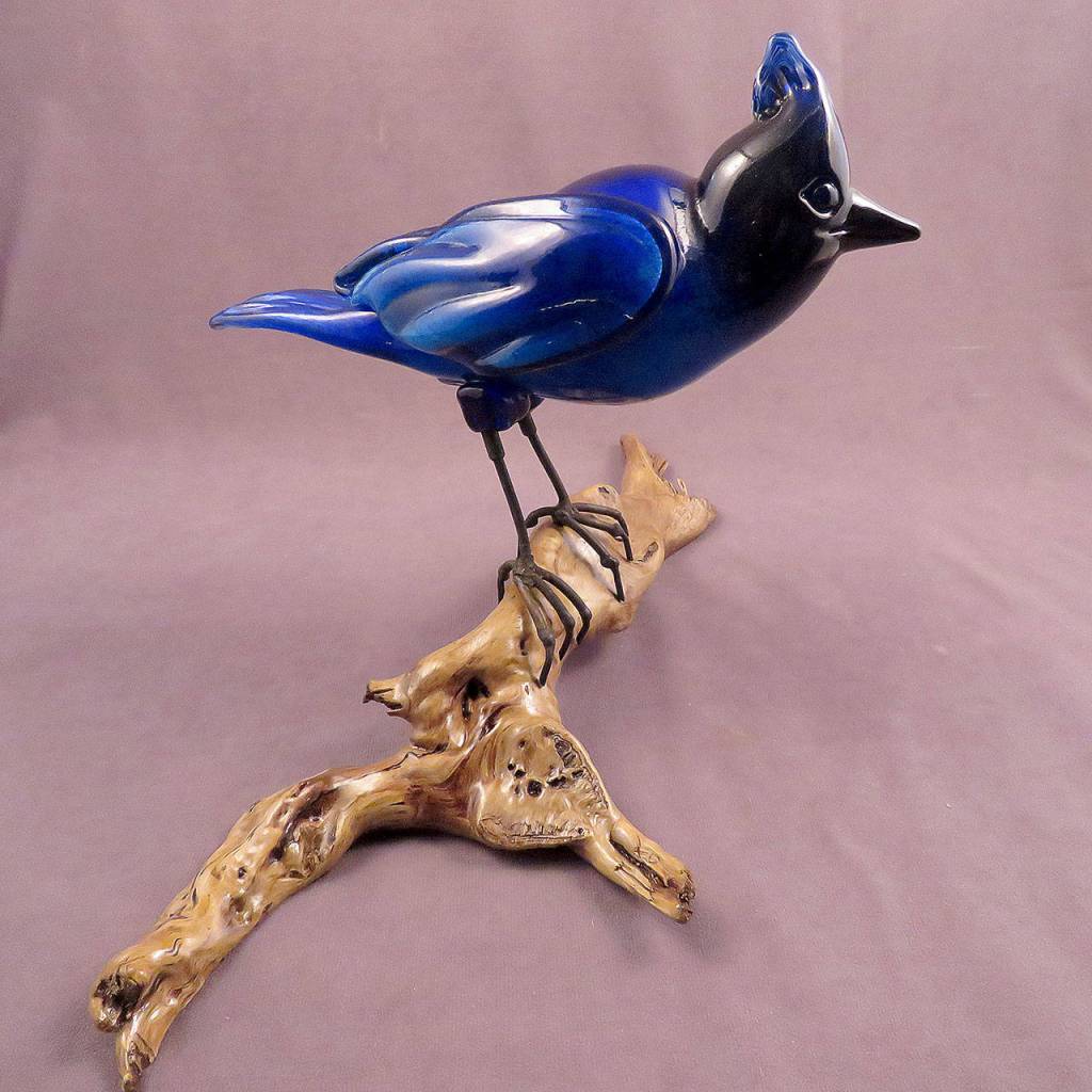 This steller jay perched on driftwood by glass artist Mark Ellinger is part of the Camano Arts Associations fall art sale. (Glass Quest Studio)