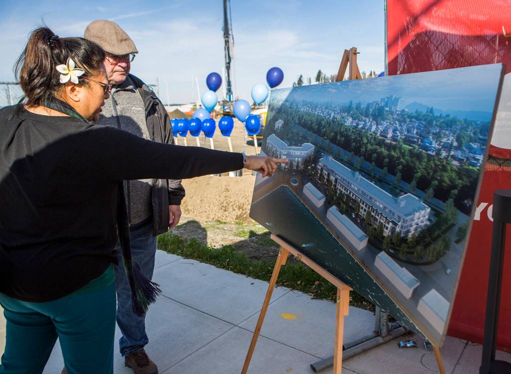Future residents try to locate where their apartment may be on a pasteboard of the apartment buildings at the groundbreaking for the Waterfront Place Apartments along the Everett waterfront Wednesday . (Olivia Vanni / The Herald)