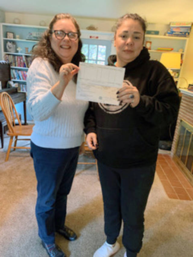 Monroe Gospel Womens Mission director Adriana Moreno and administrative assistant Linda Stima hold up a $1,500 check from Providence General Foundation in Everett. (Monroe Gospel Womens Mission)