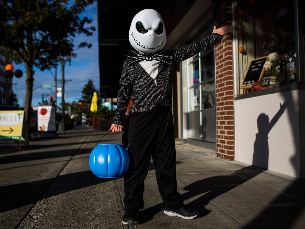 Samuel Pincus, dressed as Jack Skellington from Nightmare Before Christmas, gestures to people to come and grab candy during downtown trick-or-treating Thursday in Everett. (Olivia Vanni / The Herald)