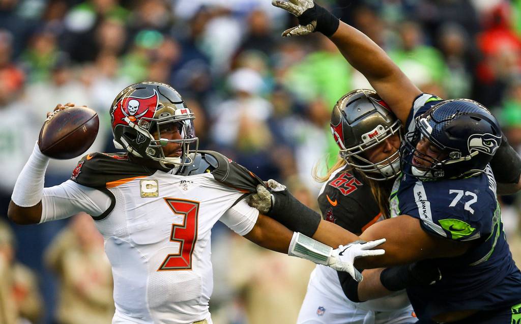 Buccaneers Jameis Winston with the help of teammate Alex Cappa works free of Seahawks Al Woods Sunday afternoon at CenturyLink Field in Seattle on November 3, 2019. (Kevin Clark / The Herald)