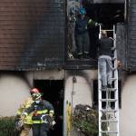 Fire investigators, right, talk as firefighters remove debris after a fatal fire at 6707 196th St. SW on Monday in Lynnwood. (Andy Bronson / The Herald)