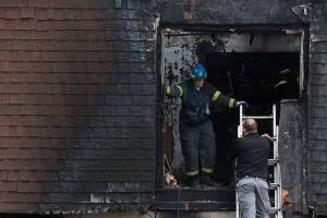 Fire investigators, right, talk as firefighters remove debris after a fatal fire at 6707 196th St. SW on Monday, Nov. 4, 2019 in Lynnwood, Wash. (Andy Bronson / The Herald)