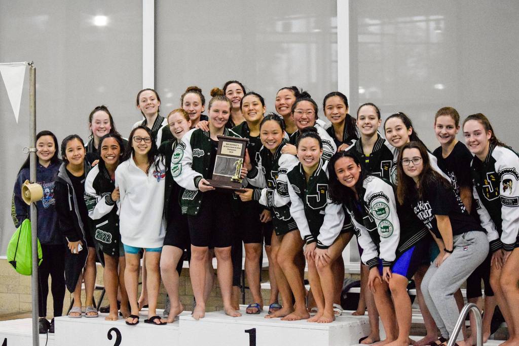 The girls Jackson swim team poses with the 4A Girls Northwest District Championship trophy on Nov. 9 at the Snohomish Aquatic Center. (Katie Webber / The Herald)