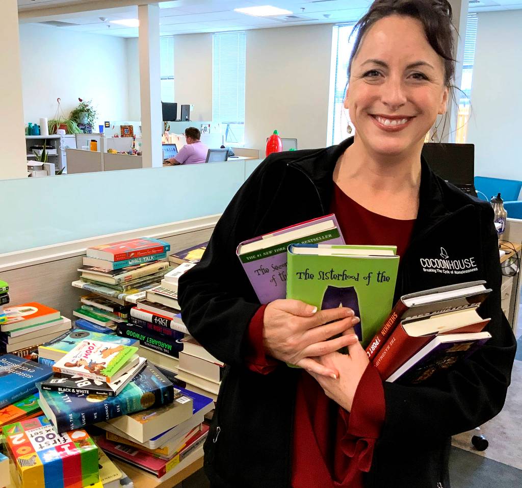 photos from Womans Book Club of Everett                                Becky Whitefield, marketing coordinator at Cocoon House, shows off some of the gift books. In celebration of its 125th anniversary, the Everett Womans Book Club has donated more than $3,000 worth of new books to the agency that shelters homeless teens and young adults.