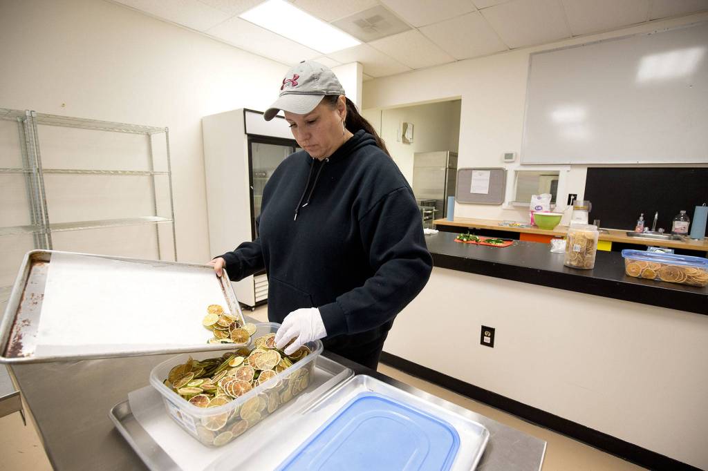 Jeannie Dalton, co-owner of Firewater Events, scoops dried limes into a container while renting the PNW Commissary Kitchen in Marysville. (Andy Bronson / The Herald)                                Jeannie Dalton, co-owner of Firewater Events, scoops dried limes into a container while using the PNW Commissary Kitchen on Monday, Nov. 18, 2019 in Marysville, Wash. (Andy Bronson / The Herald)