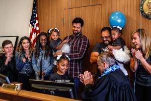 Arlingtons Avellaneda family join Judge David Kurtz at his bench as Mayah, 6, strikes his gavel Friday, National Adoption Day. Mayah and her two younger sisters, Alayna, 2, and Malaya, 1, were adopted by Jen (right) and Cid Avellaneda (next to Jen). Other family members are (from left) the Avellanedas son-in-law, Blake King, their daughter, Mariah King, their other adopted daughter, Nicole, 13, and their son, Jeriah Avellaneda, 26, holding Alayna. (Dan Bates / The Herald)