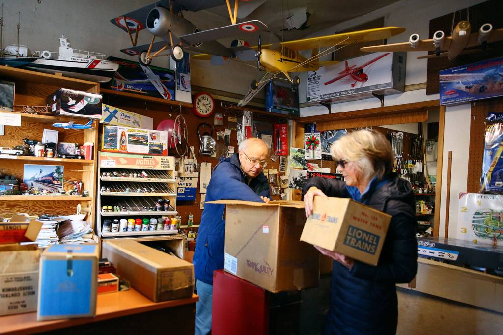 Richard Hunt, owner of the Edmonds Hobby Shop, helps Jan Schlameus with an appraisal of a train set from her youth. (Kevin Clark / The Herald)