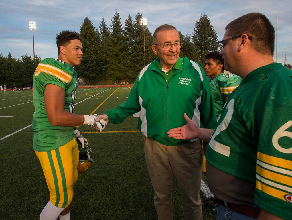 Tumwaters Thomas Drayton (left) and a well-wisher congratulate former Thunderbirds coach Sid Otton after the field was renamed in his honor in 2017. (Drew Perine / The Olympian)