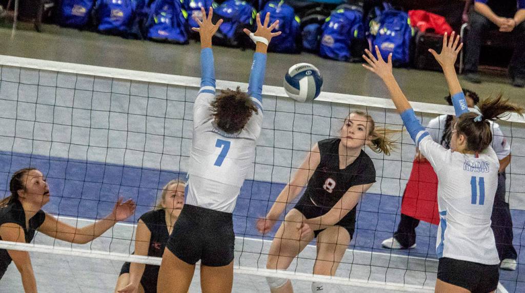 Monroes Sarah Day (8), spikes through West Valleys (Yakima) Payton Jones (7) and Alyssa Smith (11), in the semifinal round of the WIAA State Volleyball tournament Nov. 17, 2018, at the SunDome in Yakima. (TJ Mullinax / For The Herald)