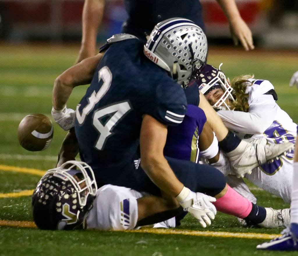 Lake Stevens Junior Robinson (bottom) and Lake Stevens Drew Carter (right) force a fumble by Glacier Peaks Ryan Black Friday night at Veterans Memorial Stadium in Snohomish on October 11, 2019. (Kevin Clark / The Herald)