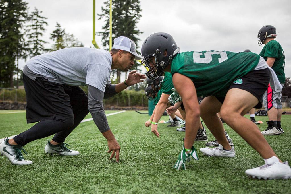 Coach JR Wells gets in a defensive stance against Exavier Bonifacio during the first day of Jackson High School football practice on Wednesday, Aug. 21, 2019 in Mill Creek, Wash. (Olivia Vanni / The Herald)