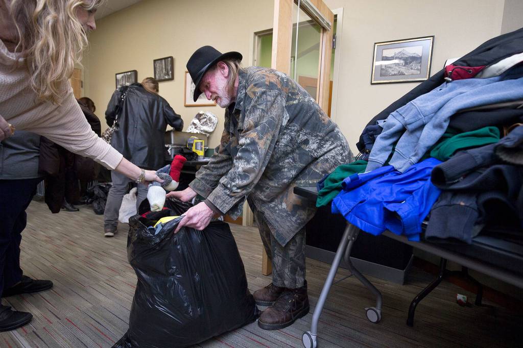 Carie Clayton, left, puts socks into Kevin Drakes bag at the Winter Clothes Giveaway, sponsored by the Angel Resource Connection in the Granite Falls Library. (Andy Bronson / The Herald)