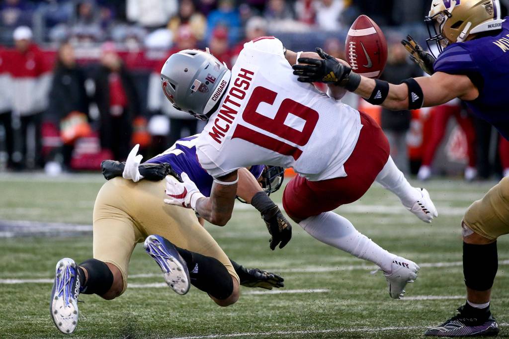 Washington State running back Deon McIntosh (16) fumbles the ball after a hit by defensive back Trent McDuffie. (Kevin Clark / The Herald)