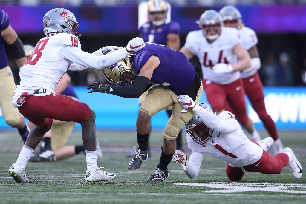 Washington State Cougars cornerback George Hicks III (18) and safety Tyrese Ross try to stop Washington Huskies wide receiver Aaron Fuller. The Washington State University Cougars lost 31-13 to the University of Washington Huskies in the 112th Apple Cup at Husky Stadium on Friday, Nov. 29, 2019 in Seattle, Wash. (Andy Bronson / The Herald)