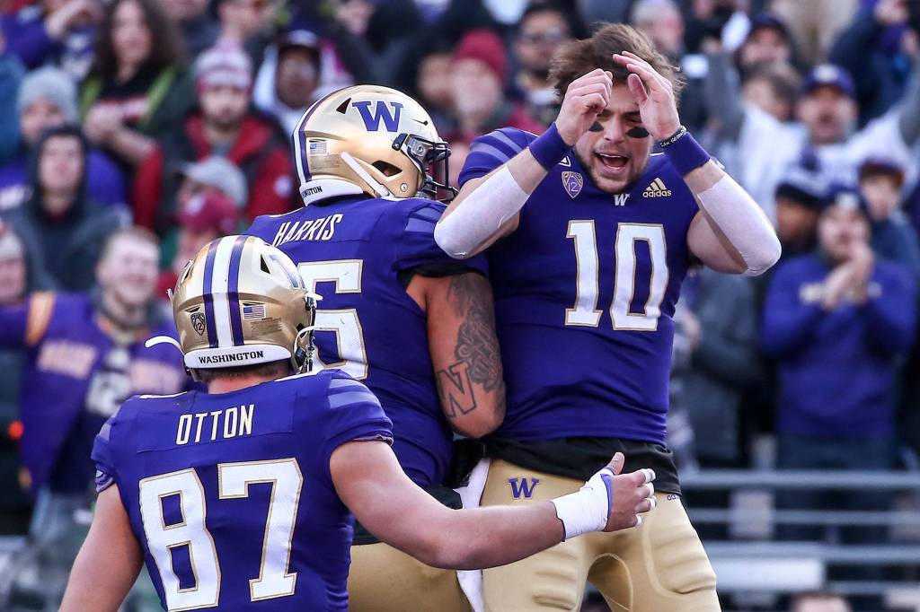 Washington quarterback Jacob Eason (10) celebrates his first-quarter touchdown run with tight end Cade Otton (87) and center Nick Harris. (Kevin Clark / The Herald)