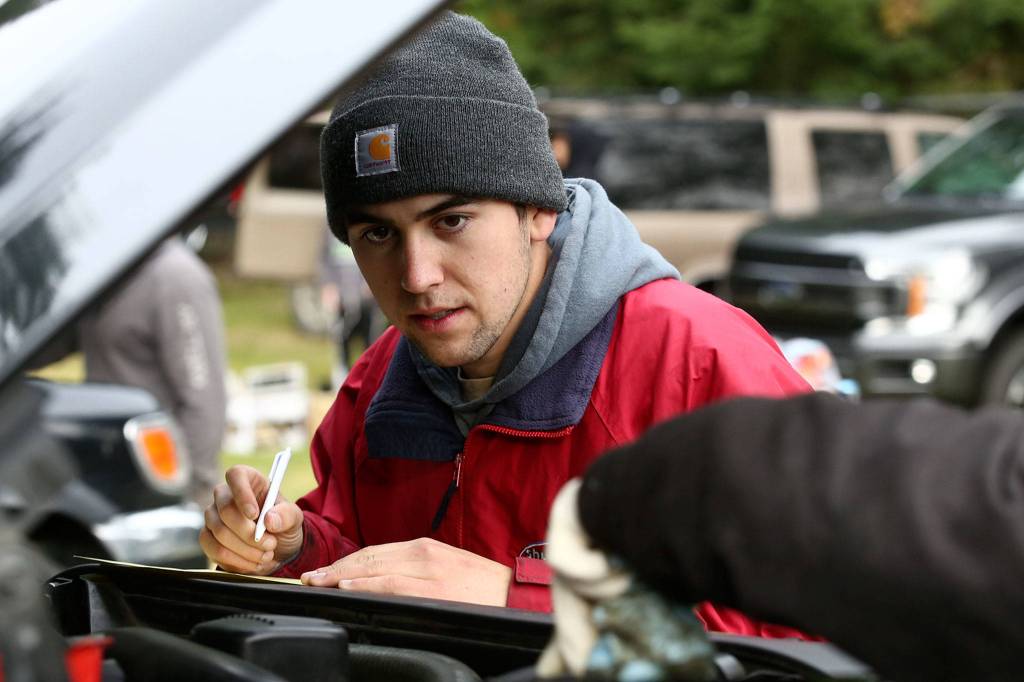 Chris Day records maintenance of a car at View Church in Snohomish in October. (Kevin Clark / The Herald)