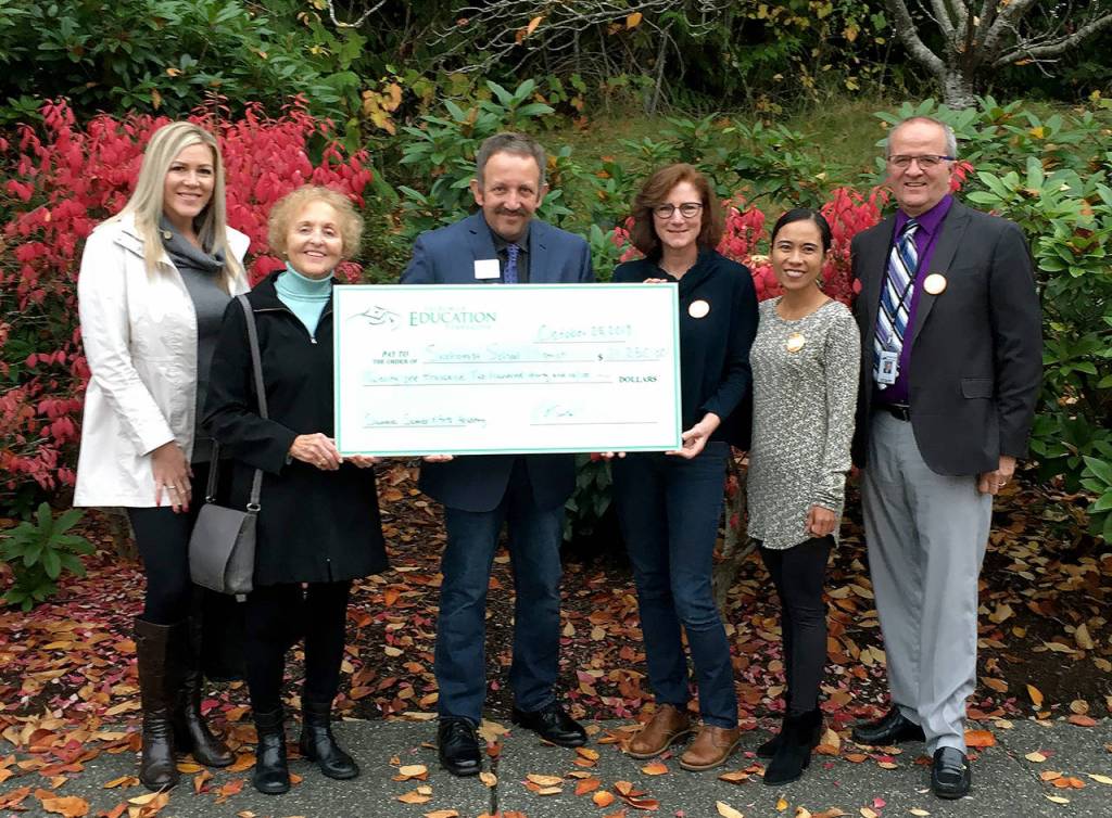 Snohomish Education Foundation board members and school leaders hold up a check for $21,000, which will go toward the Snohomish School Districts Summer Science and Arts Academy. (Snohomish Education Foundation)