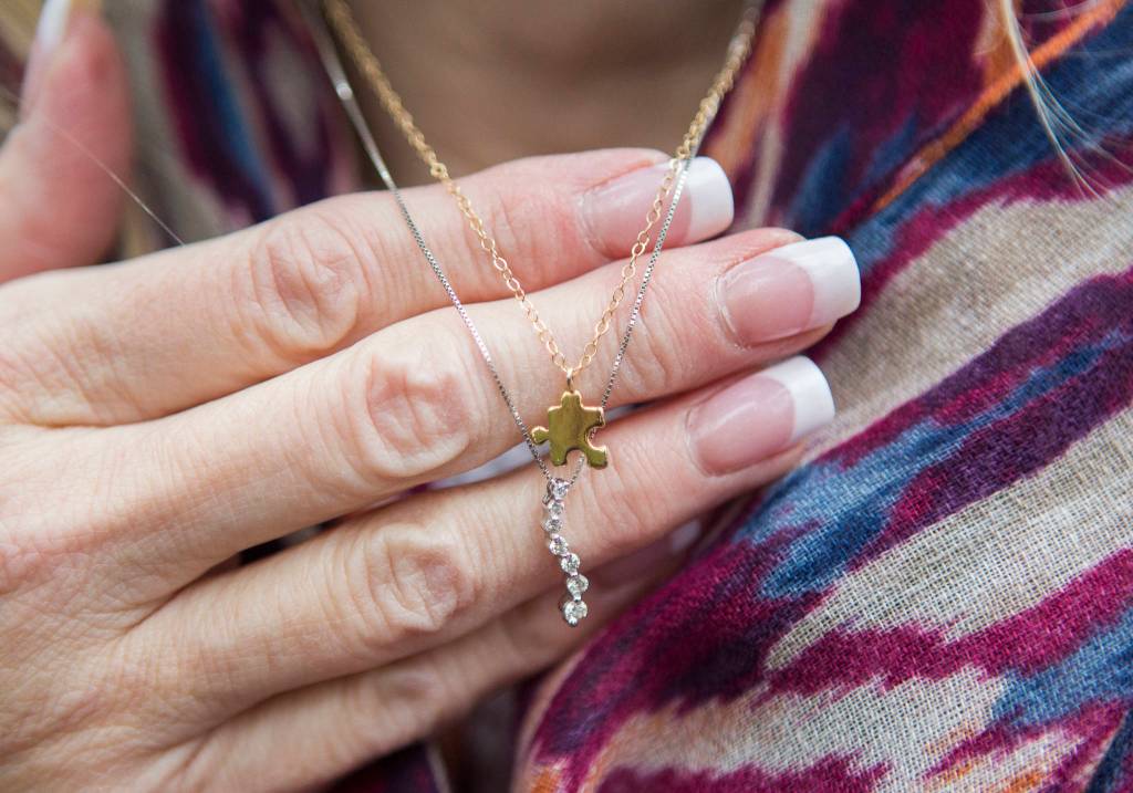 Kelly Howell wears a small gold puzzle piece necklace, given to her by her half-sister, Linda Holt, who wears her own puzzle piece that fits together with Howells necklace. (Olivia Vanni / The Herald)