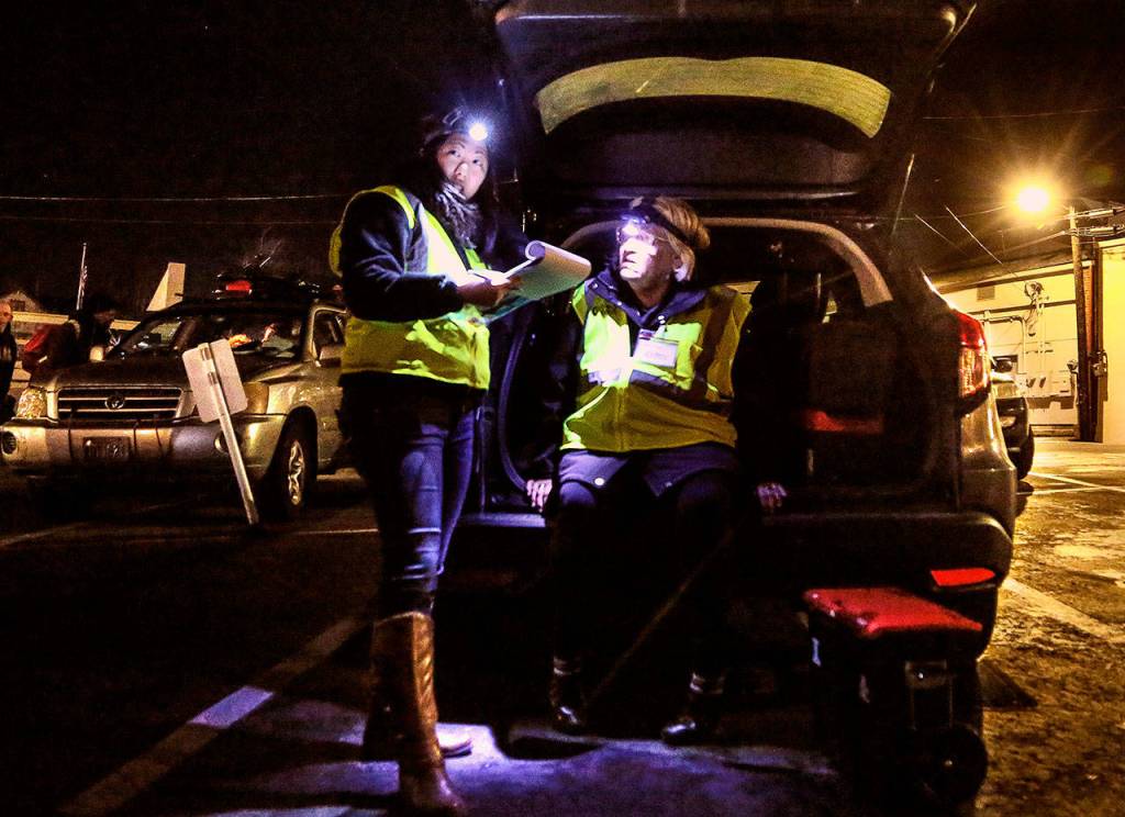 Gail Pyper (seated), a school nurse by day, talks with medical scribe Amanda Dahl near the Everett Public Library recently while on an evening outing with MercyWatch. (Dan Bates / The Herald)