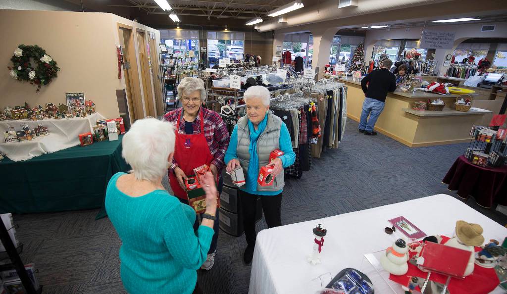 Volunteer Eunice Smith, left, and Sandi Sharp, right, talk with another volunteer in the Assistance League of Everett thrift store. (Andy Bronson / The Herald)