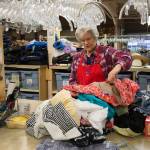 Volunteer Eunice Smith checks for stains and and other defects in clothing donations at the Assistance League of Everett. (Andy Bronson / The Herald)