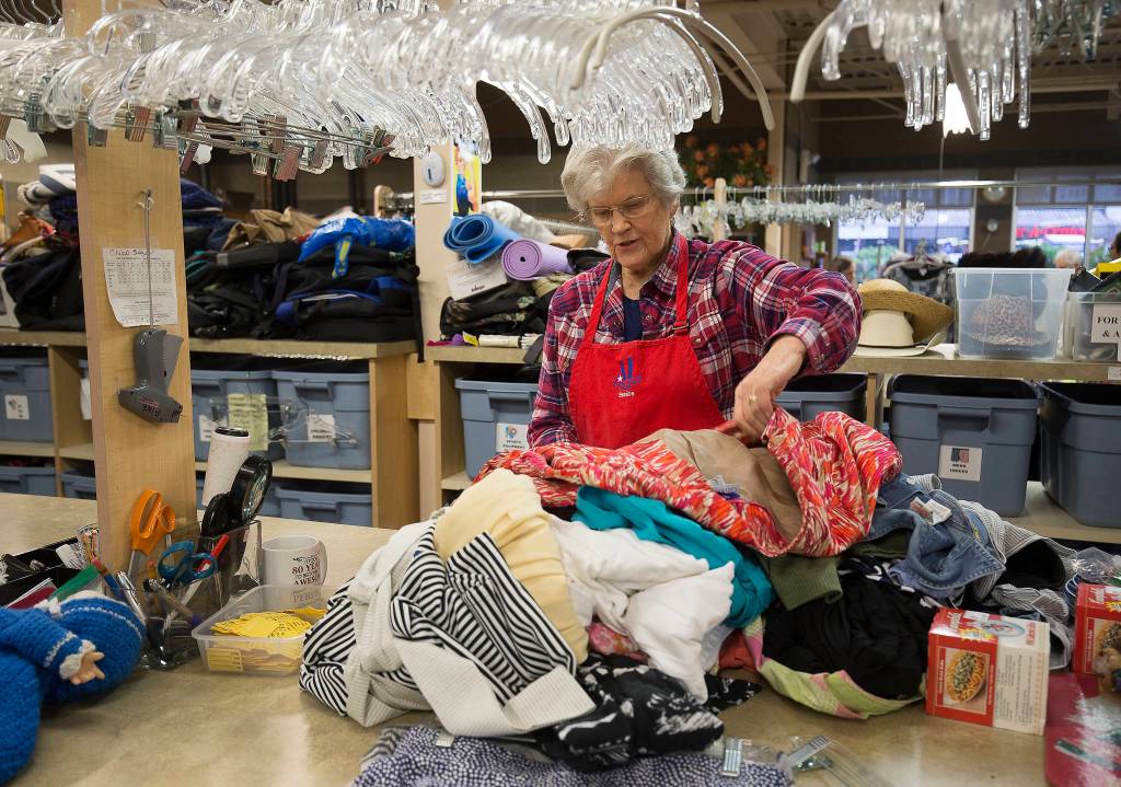 Volunteer Eunice Smith checks for stains and and other defects in clothing donations at the Assistance League of Everett. (Andy Bronson / The Herald)